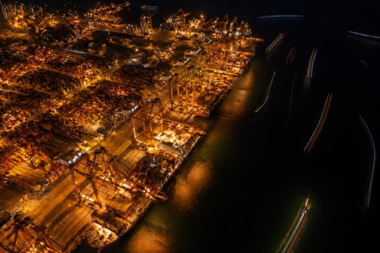 Containerhafen Luftbild bei Nacht, goldene Kräne, Schiffslichtspuren — AWG Außenwirtschaftsstrafrecht