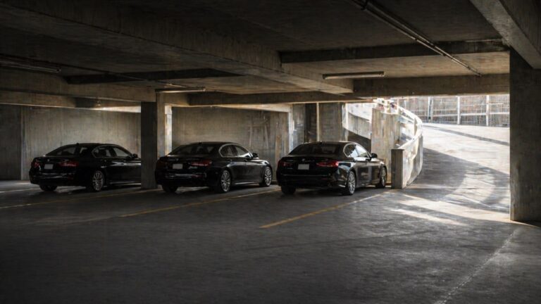 Drei schwarze BMW-Limousinen in einem Parkhaus — Symbol für Kartellabsprachen und Unternehmensverteidigung im Kartellbußgeldverfahren