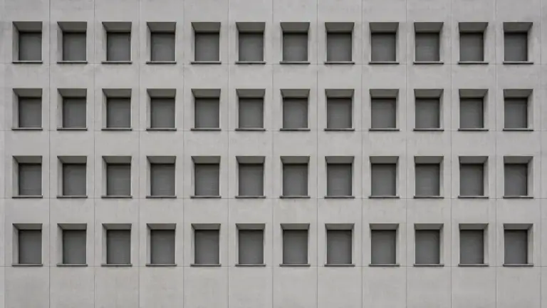 Strenges Fensterraster einer Behördenfassade — Steuerhinterziehung und Selbstanzeige nach § 370 AO.