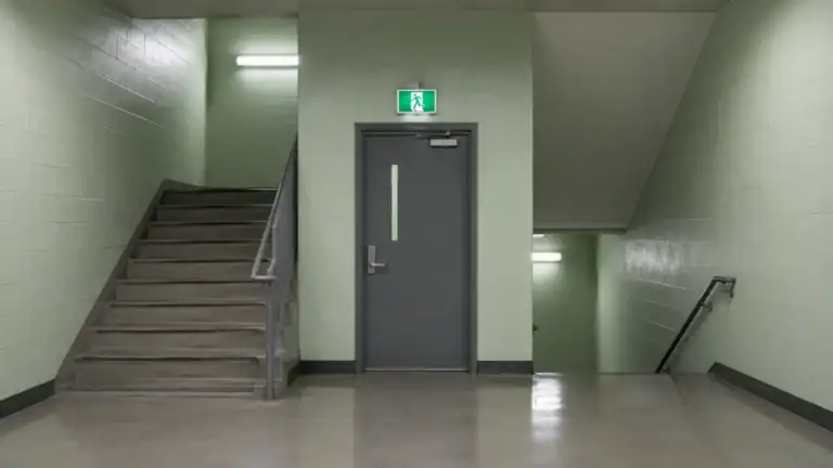 Institutionelles Treppenhaus mit Notausgangsschild — Behördenarchitektur im Strafverfahren.