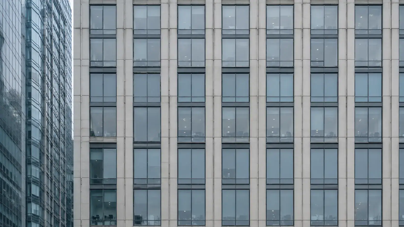 Gleichförmige Bürofassade mit Betonraster und Glasflächen — Metapher für strukturierte Vorstandsverantwortung.