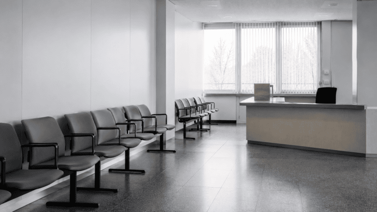 Leeres Behörden-Wartezimmer mit grauen Stühlen und Empfangspult — Kartellbußgeldverfahren und Kronzeugenstatus nach § 298 StGB.