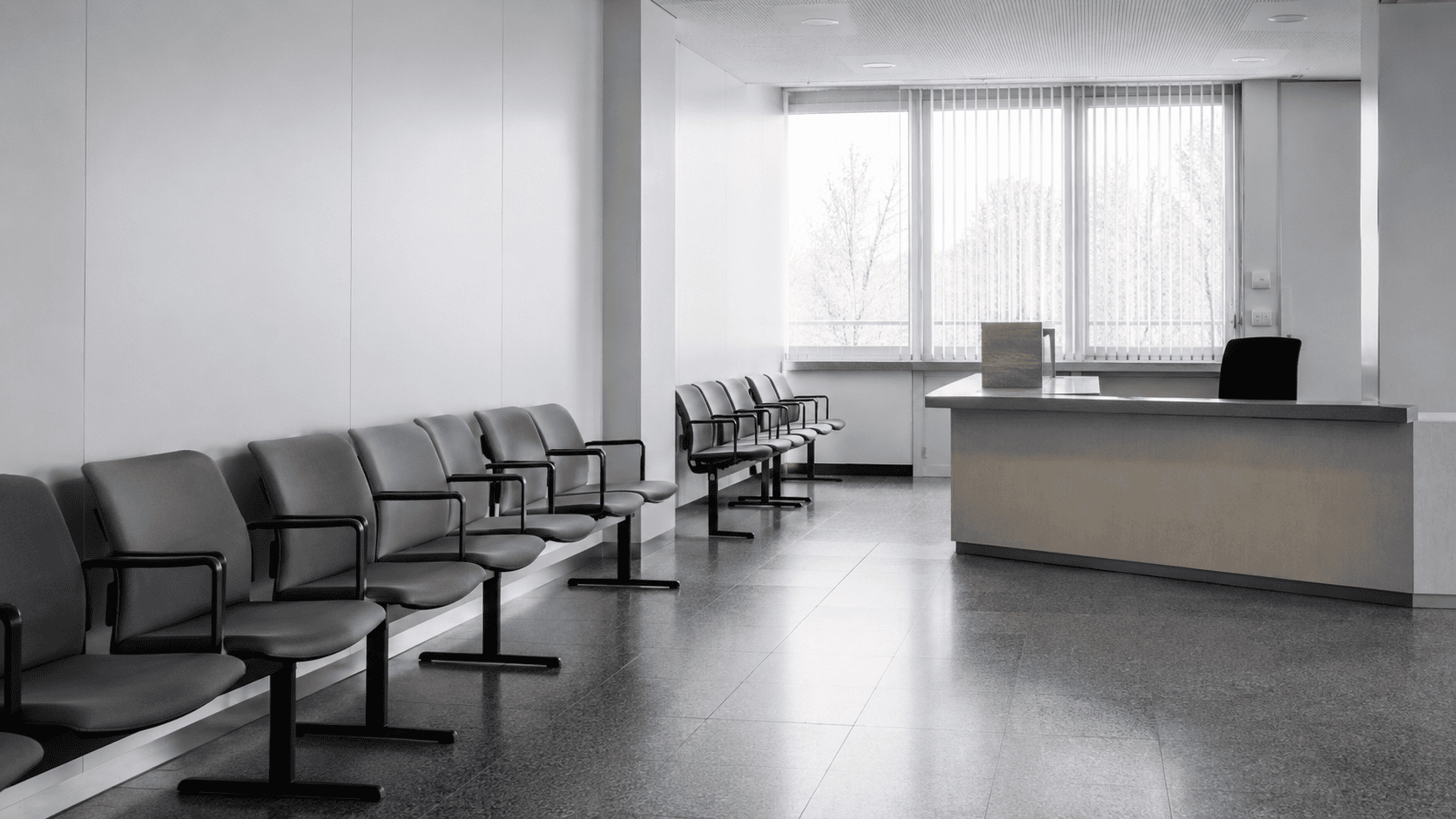 Leeres Behörden-Wartezimmer mit grauen Stühlen und Empfangspult — Kartellbußgeldverfahren und Kronzeugenstatus nach § 298 StGB.