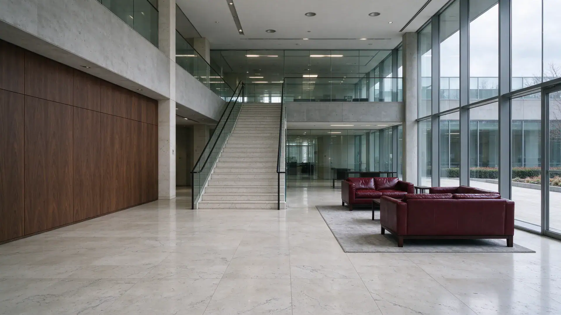 Eingangshalle einer Unternehmenszentrale mit Kalksteinboden, Ledersofas und seitlicher Freitreppe (Symbolbild, KI-generiert)
